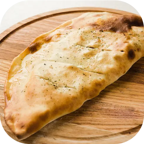 Calzone horneado dorado de La Chilenita sobre bandeja redonda de madera