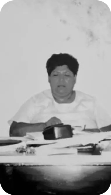 Fotografía en blanco y negro de la fundadora de La Chilenita sentada frente a una mesa con documentos.