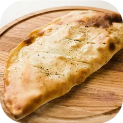 Calzone horneado dorado de La Chilenita sobre bandeja redonda de madera